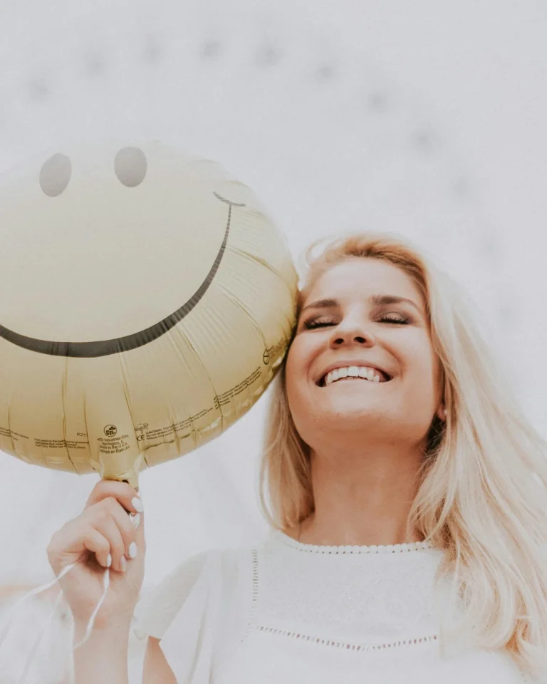 Mulher segurando um balão sorridente, ilustrando artigo sobre o impacto do pensamento positivo na sua saúde e longevidade, pela adnlife.pt